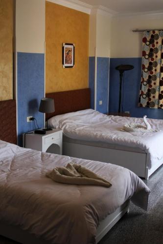 two beds in a room with blue walls at Nile Valley Hotel in Luxor