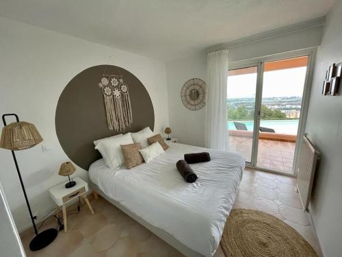 une chambre avec un grand lit avec une grande fenêtre dans l'établissement Duplex vue mer piscine privative, à Mandelieu-la-Napoule