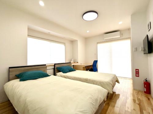 two beds in a room with a large window at プライベートサウナ付 -円テラス en terrace- 奄美大島の一棟貸切 in Tatsugo