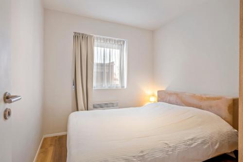 a white bedroom with a bed and a window at Chez Victorine Kortrijk in Kortrijk
