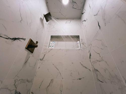 a white tiled bathroom with a shower with a mirror at Barrel Oak Mansion- Fire pit, & pool table NR TTU in Lubbock
