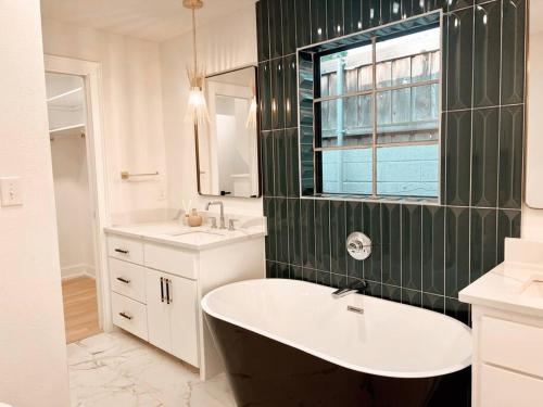 a bathroom with a tub and a sink and a window at Barrel Oak Mansion- Fire pit, & pool table NR TTU in Lubbock