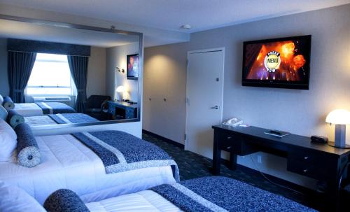 a hotel room with two beds and a tv on the wall at Ramada Plaza by Wyndham West Hollywood Hotel & Suites in Los Angeles