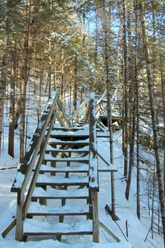 a wooden bridge in the woods in the snow at Au Chic Chalet des Chutes Chic Chalet in Sainte-Melanie