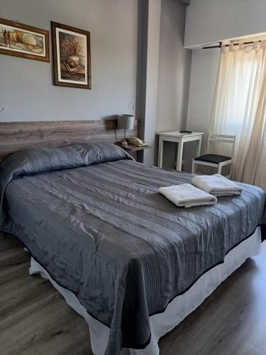 a bedroom with a large bed with two towels on it at Hotel Iberia in Neuquén