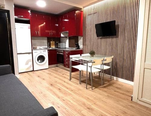 a kitchen with red cabinets and a table and a microwave at CHUECA Apartamentos Noxi in Madrid