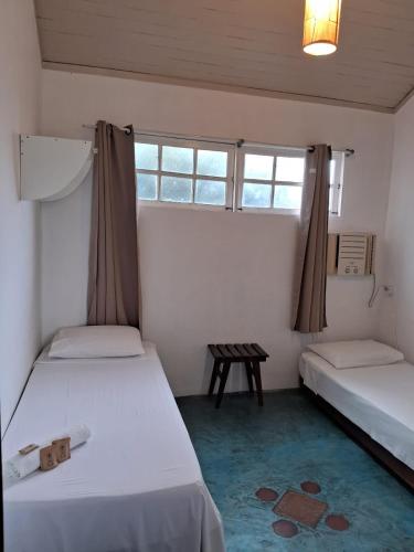 a room with two beds and a table and windows at Atobá Villas in Paraty