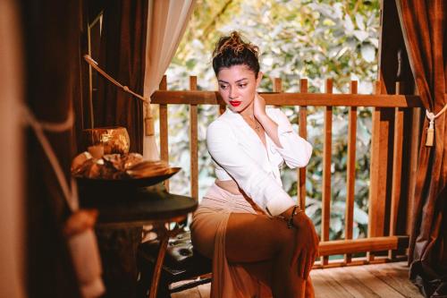 a woman is sitting on a porch at West Indies Cottage in Pointe-Noire