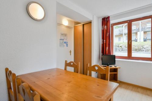 une salle à manger avec une table en bois et une télévision dans l'établissement Studio entre Lac et Montagnes Evian - Lugrin, à Lugrin