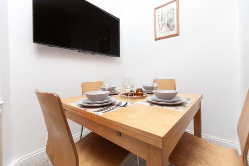 a wooden table with chairs and a television on a wall at Beautiful 3 Bedroom Flat In Scott Ellis Gardens in London