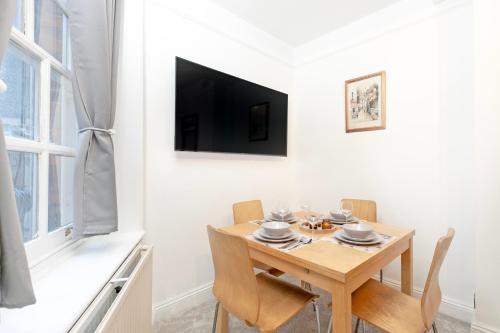 a dining room table with chairs and a television on a wall at Beautiful 3 Bedroom Flat In Scott Ellis Gardens in London