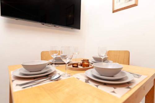 a wooden table with plates and wine glasses on it at Beautiful 3 Bedroom Flat In Scott Ellis Gardens in London