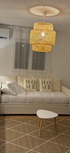 a living room with a white couch and a chandelier at Le Cocon du Paradis à 4 min du Zoo de Beauval in Saint-Aignan