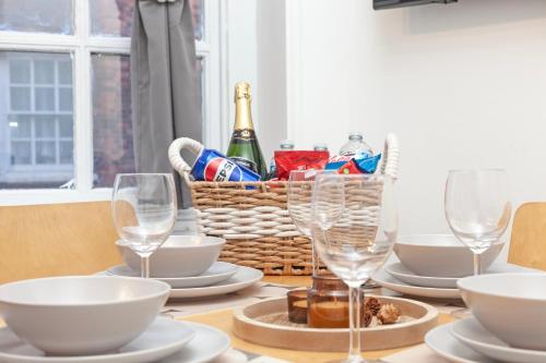 a table with wine glasses and a basket of wine bottles at Beautiful 3 Bedroom Flat In Scott Ellis Gardens in London