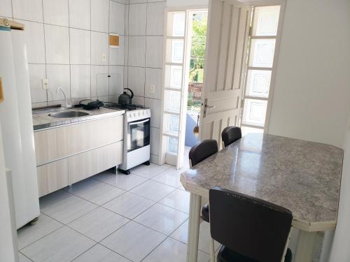 a kitchen with a counter and a table with chairs at Refúgio Minimalista Tranquilidade a 600m da Praia in Governador Celso Ramos