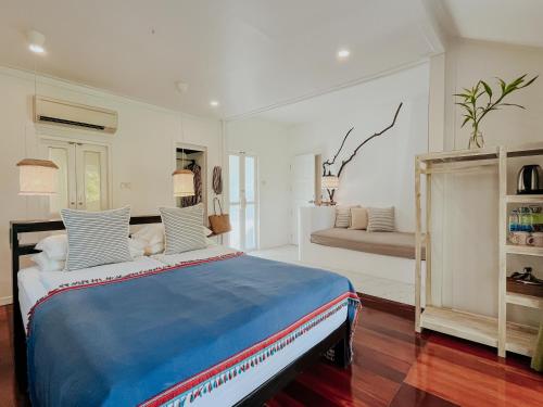 a bedroom with a blue and white bed and a couch at Baan Bua Cottage SHA EXTRA PLUS B5510 in Ko Kood