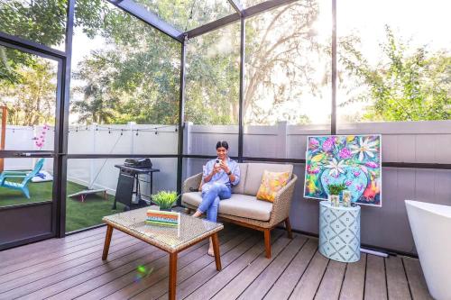 a woman sitting on a couch on a patio at FunTropicalTinyHomeGolfCartLake in Orlando