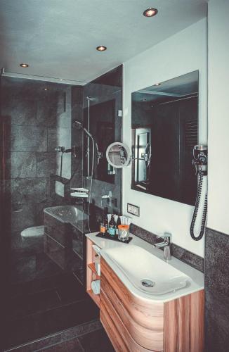 a bathroom with a sink and a shower at Hotel Alpenkönig in Oberstaufen
