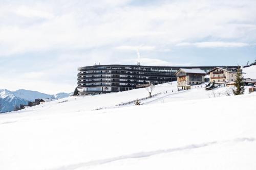 a building on top of a snow covered mountain at Familienhotel Familiamus in Maranza