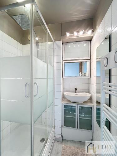 une salle de bain avec une douche en verre et un lavabo dans l'établissement Sable & Horizon - Vue Mer - 7e étages, à Bray-Dunes
