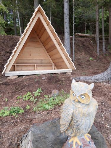 an owl statue sitting on a rock in front of a doghouse at Sunflower House with Jacuzzy and Sauna in Vitanje