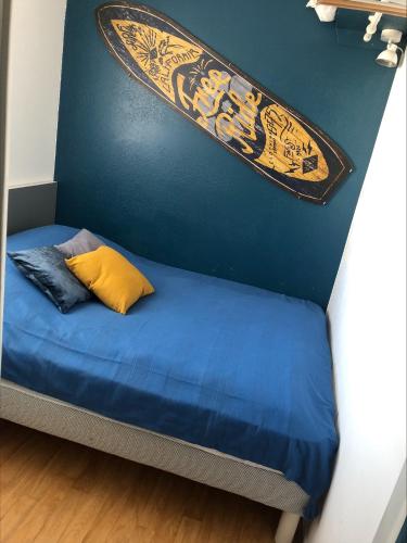 un lit avec une planche de surf accrochée au mur dans l'établissement Appartement Le Beaufort, à Saint-Gilles-Croix-de-Vie