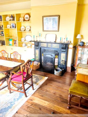 a living room with a fireplace and a table and chairs at Portland House in Whitchurch