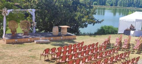 an outdoor ceremony with chairs and a table and water at Hotel Restaurant La Dame du Lac in Monflanquin