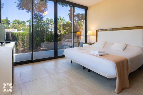 ein Schlafzimmer mit einem großen weißen Bett und großen Fenstern in der Unterkunft Villa Alex by Abahana Villas in Benissa