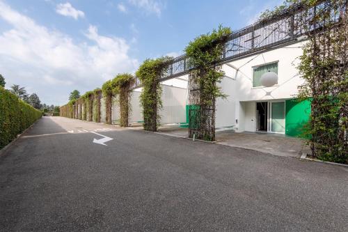 an empty road next to a white building with vines at MO.OM Hotel in Olgiate Olona