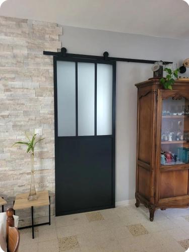 - une porte coulissante noire dans une chambre dotée d'un mur en briques dans l'établissement La petite maison, à Pontis