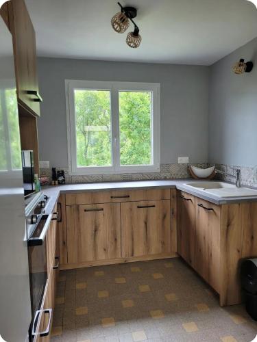 une cuisine avec des armoires en bois et une fenêtre dans l'établissement La petite maison, à Pontis