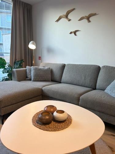 a living room with a table and a couch and birds at Quality Time appartement met gesloten garagebox in De Panne