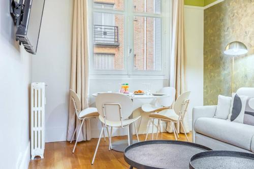 un salon avec une table, des chaises et un canapé dans l'établissement Confort et tranquillité à Neuilly-sur-Seine, à Neuilly-sur-Seine