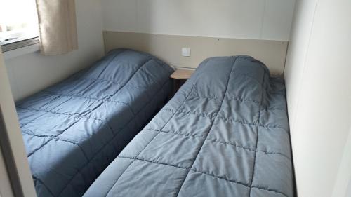 - deux lits dans une petite pièce dans l'établissement MH 538 TOUT EQUIPE et TOUT CONFORT 2ch 1sdb dans camping 4 étoiles, à Saint-Julien-en-Born