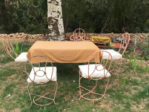 a table and four chairs around a table and a tree at Hôtel panoramique de la vallée in Aït Idaïr