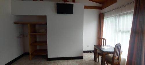 a dining room with a table and a tv on a wall at Alisson Hotel y Restaurant in Monteverde Costa Rica