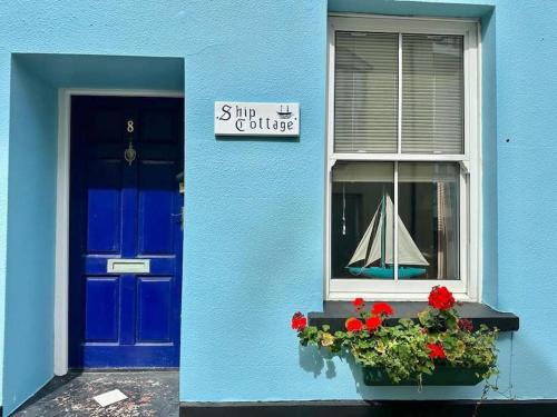 a blue building with a window with a toy boat in a window at Ship Cottage Tenby Beach 50m in Pembrokeshire