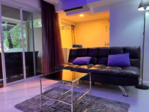 a living room with a black couch with purple pillows at Mama Beach Residence - Adults Only in Phi Phi Don