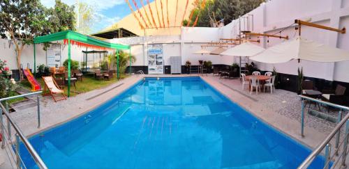 a large blue swimming pool with tables and umbrellas at Hotel Santa Maria in Ica
