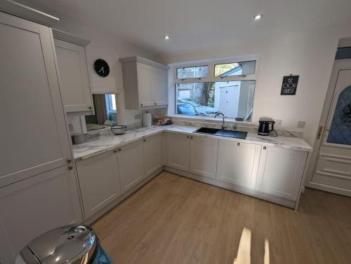 a kitchen with white cabinets and a sink and a window at Luxurious Georgian Town House in Langholm