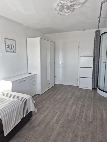 a white bedroom with a bed and a dresser at Helles 1-Zimmer-Apartment mit guter Ausstattung in Merzig
