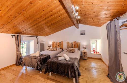 une chambre avec deux lits et un plafond en bois dans l'établissement Gîtes Domaine des 4 Mas - LA HOWLITE - LE LARIMAR - L'AMAZONITE, à Sembas