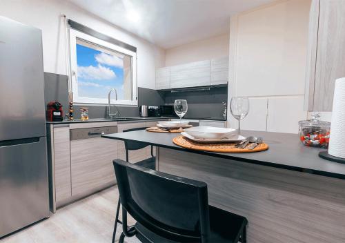 une cuisine avec une table et deux verres de vin dans l'établissement l'évidence-Bâle-Aéroport-Lockeys, à Saint-Louis