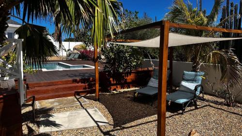 a patio with two chairs and an umbrella and a pool at The Rocks Residence, apartment 2 of total 2 in Paradera