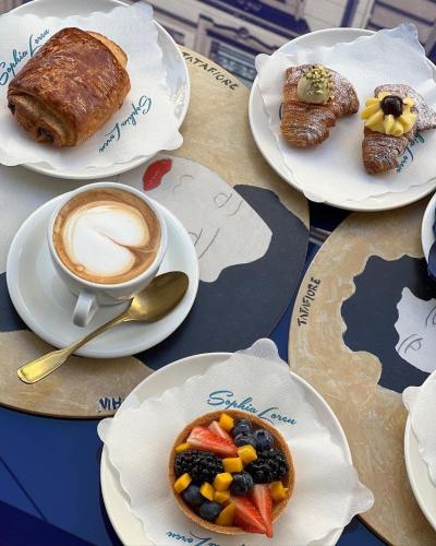 a table with plates of food and a cup of coffee at Green Park Penthouse Suite & Pool - Heated Pool - in Bari