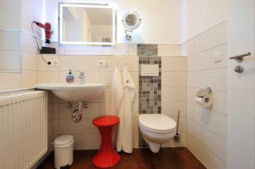 a bathroom with a sink and a toilet and a mirror at Lausitzer Ferienapartment Stube in Bernsdorf