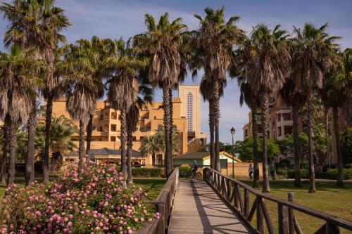 a walkway in a park with palm trees and flowers at Vila Gale Isla Canela in Isla Canela
