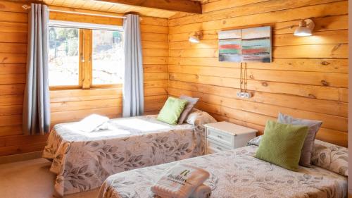 une chambre avec deux lits dans une cabane en rondins dans l'établissement Miralvalle El Gastor by Ruralidays, à El Gastor