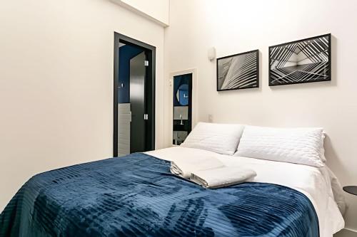 a white bedroom with a blue blanket on a bed at Loft moderno e espaçoso no centro de Floripa -UN30 in Florianópolis